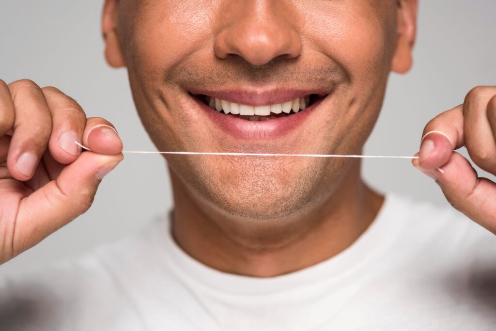 Clínica Dental Sorias - Blog - El uso del hilo dental - Hombre con hilo dental