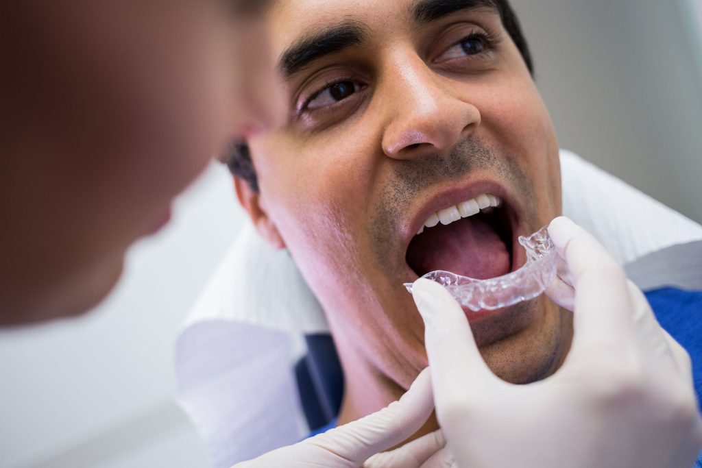 Clínica Dental Sorias - Blog - dentista-ayuda-paciente-a-usar-brackets-invisibles