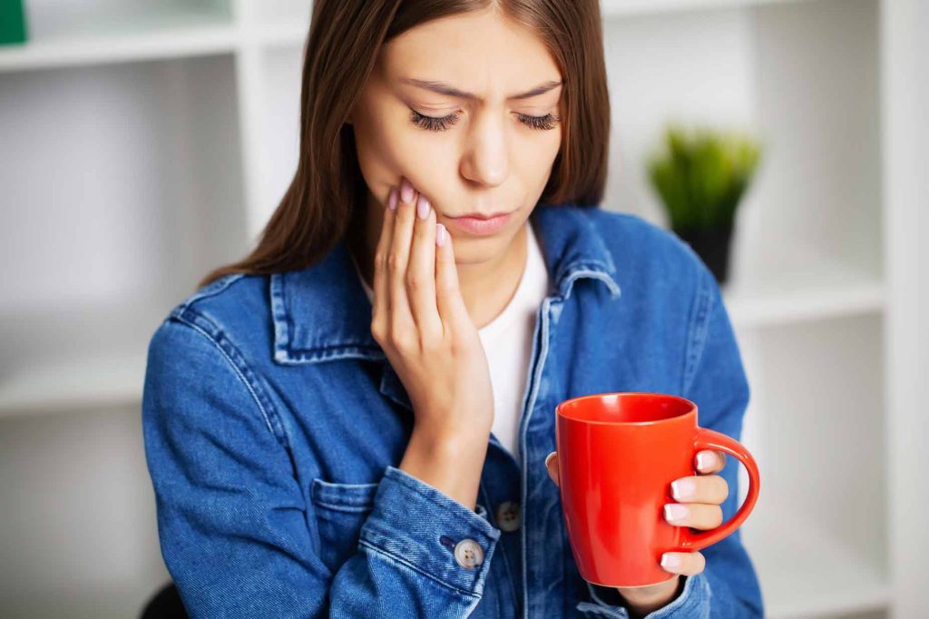 Mujer tocando su mandíbula por sensibilidad dental