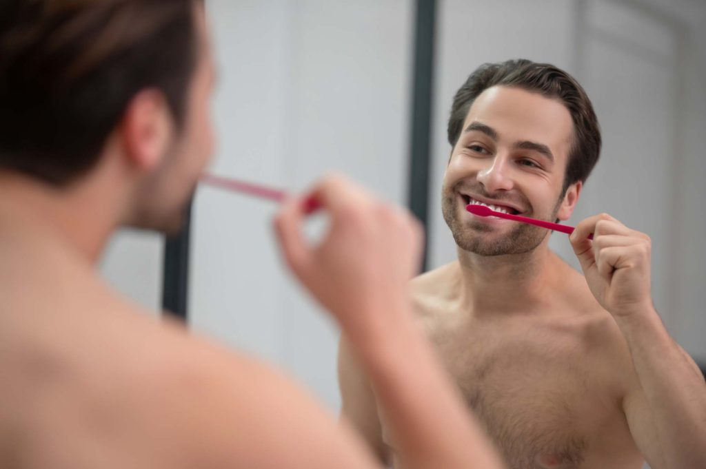 Hombre adulto cepillándose los dientes después de una limpieza dental profesional
